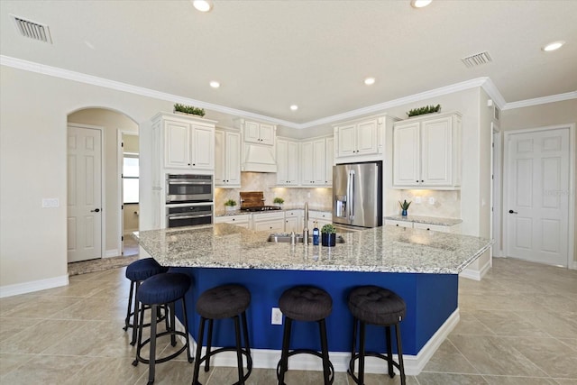 kitchen with a spacious island, a breakfast bar area, ornamental molding, light stone countertops, and appliances with stainless steel finishes