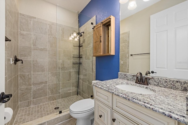 bathroom featuring vanity, a tile shower, and toilet