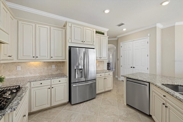 kitchen with appliances with stainless steel finishes, cream cabinets, and tasteful backsplash