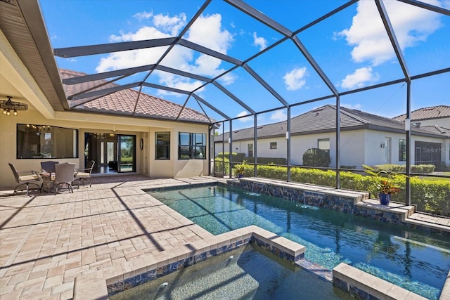 view of swimming pool featuring ceiling fan, glass enclosure, pool water feature, a patio area, and an in ground hot tub