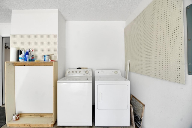 clothes washing area with a textured ceiling and separate washer and dryer