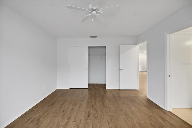 unfurnished bedroom featuring a closet, wood-type flooring, and ceiling fan