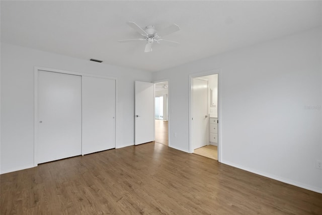 unfurnished bedroom with a closet, ceiling fan, hardwood / wood-style flooring, and ensuite bathroom