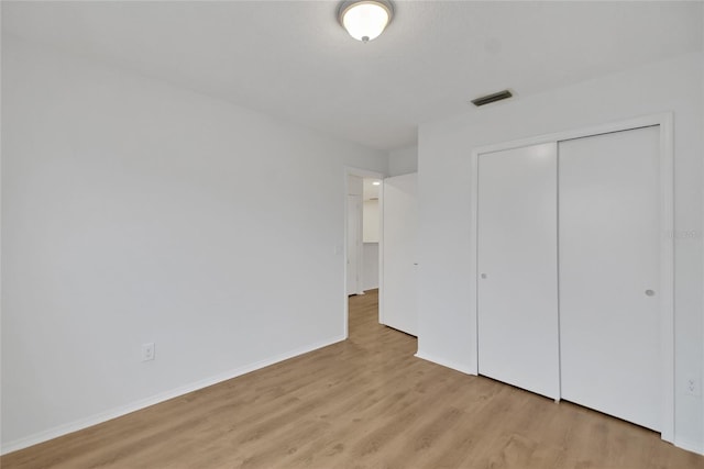 unfurnished bedroom featuring light hardwood / wood-style flooring and a closet