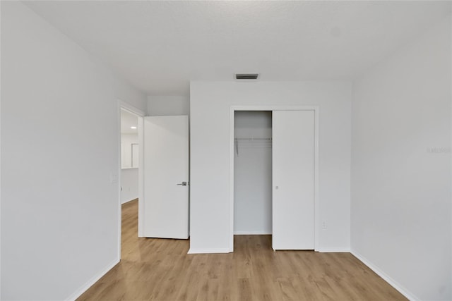 unfurnished bedroom with light hardwood / wood-style flooring and a closet