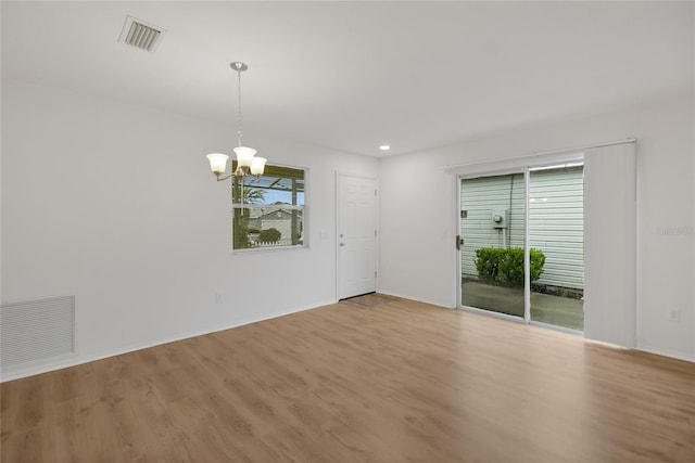 spare room featuring an inviting chandelier and light wood-type flooring