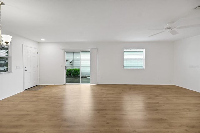 spare room featuring wood-type flooring and ceiling fan with notable chandelier