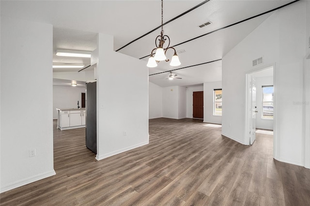 unfurnished dining area with a textured ceiling, vaulted ceiling, ceiling fan with notable chandelier, and hardwood / wood-style floors