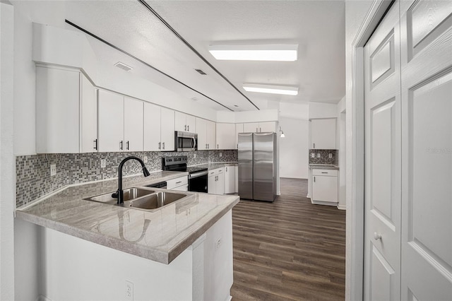 kitchen featuring sink, appliances with stainless steel finishes, kitchen peninsula, and white cabinetry