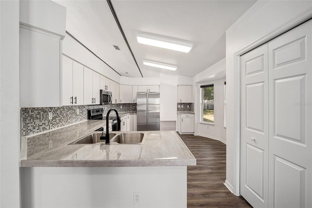 kitchen with kitchen peninsula, white cabinetry, dark hardwood / wood-style floors, sink, and stainless steel appliances