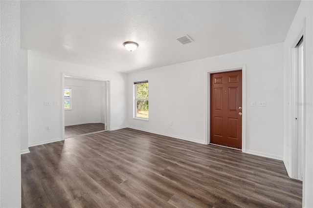 unfurnished room with a textured ceiling and dark hardwood / wood-style floors