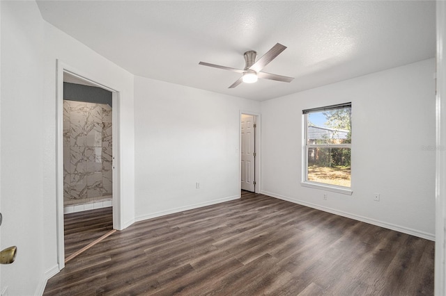 unfurnished bedroom featuring connected bathroom, ceiling fan, dark wood-type flooring, and a textured ceiling