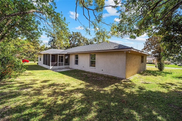 rear view of house featuring a lawn and a sunroom