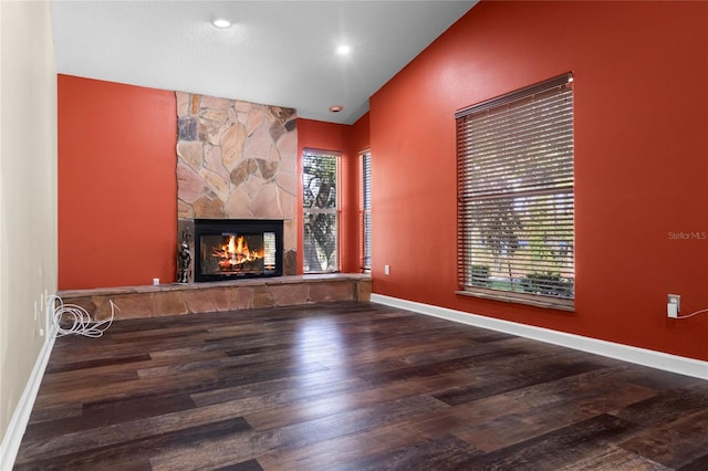 unfurnished living room featuring a stone fireplace, high vaulted ceiling, a wealth of natural light, and hardwood / wood-style floors