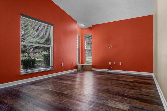 unfurnished room with lofted ceiling, wood-type flooring, and a textured ceiling