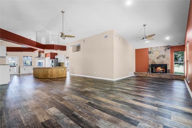 unfurnished living room featuring dark wood-type flooring, a fireplace, and high vaulted ceiling