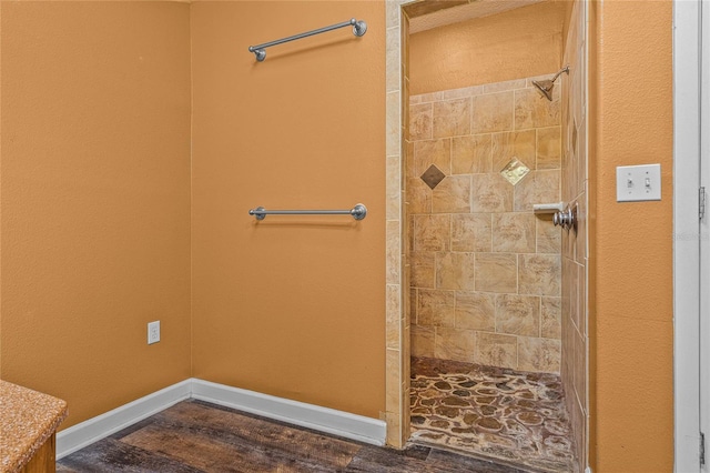 bathroom with hardwood / wood-style floors and tiled shower