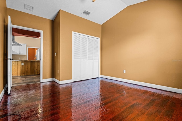 unfurnished bedroom with wood-type flooring, vaulted ceiling, and a closet