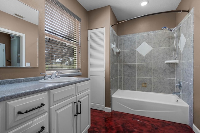 bathroom featuring tiled shower / bath, vanity, and a textured ceiling