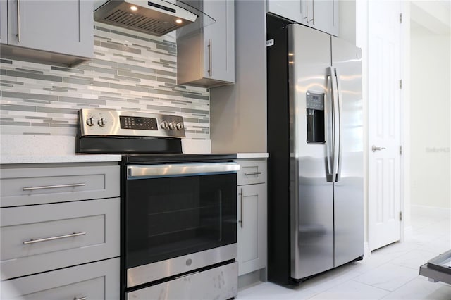 kitchen with backsplash, gray cabinets, exhaust hood, and appliances with stainless steel finishes