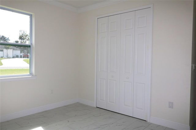 unfurnished bedroom with multiple windows, ornamental molding, and a closet