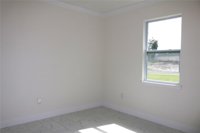 spare room with marble finish floor, ornamental molding, and baseboards