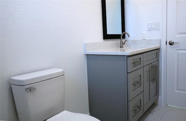 half bathroom with marble finish floor, vanity, and toilet