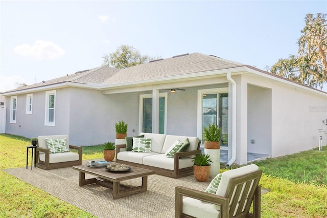 back of property featuring a shingled roof, a lawn, an outdoor living space, and stucco siding