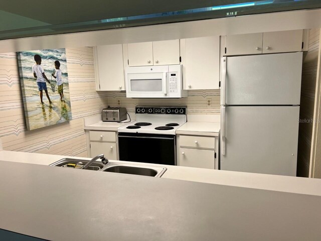 kitchen with white cabinetry, white appliances, sink, and tasteful backsplash