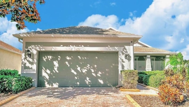 view of side of home featuring an attached garage, decorative driveway, and stucco siding