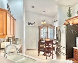 kitchen with stainless steel fridge, sink, and hanging light fixtures