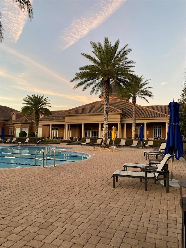 pool at dusk featuring a patio area