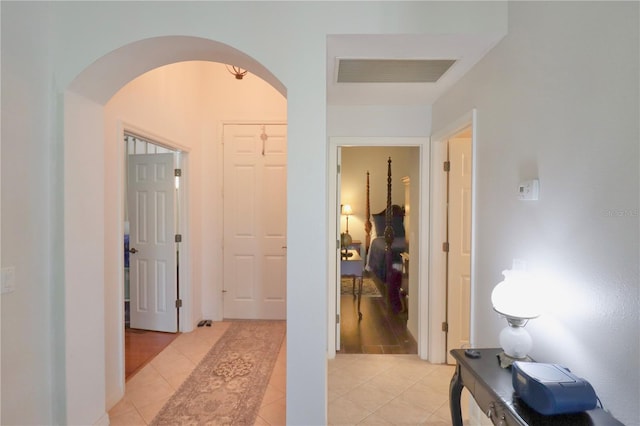 corridor featuring arched walkways, visible vents, and light tile patterned flooring