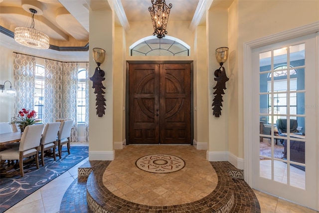 foyer entrance with beamed ceiling, a notable chandelier, light tile patterned flooring, and crown molding