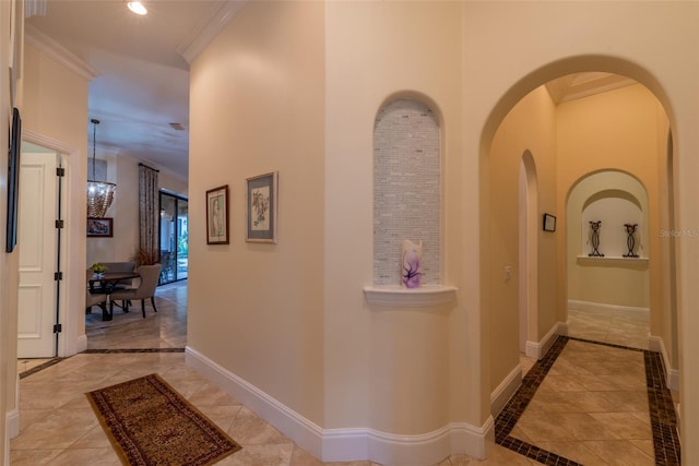 hall with light tile patterned floors, crown molding, and a chandelier