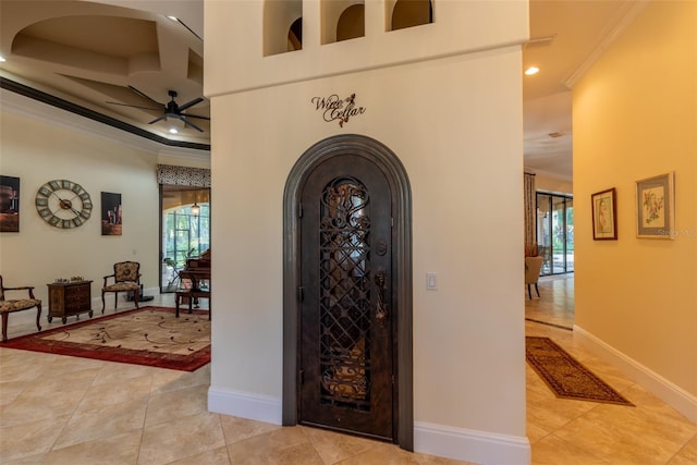 tiled entrance foyer with crown molding and ceiling fan