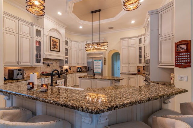 kitchen with kitchen peninsula, dark stone counters, decorative light fixtures, a kitchen bar, and high quality appliances