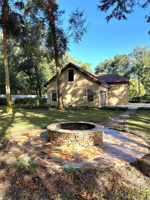 back of house featuring a fire pit, a yard, and a patio