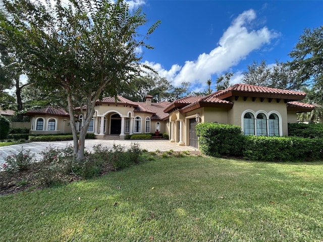 mediterranean / spanish-style home with a garage and a front lawn