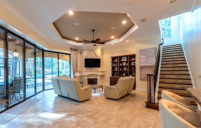 living room featuring light tile patterned floors, a raised ceiling, ceiling fan, and ornamental molding