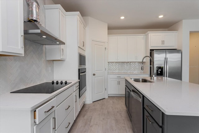 kitchen featuring wall chimney exhaust hood, sink, white cabinets, appliances with stainless steel finishes, and light hardwood / wood-style floors