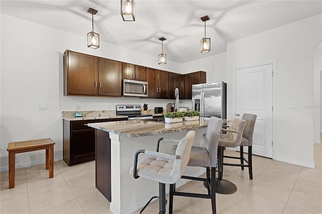 kitchen featuring an island with sink, stainless steel appliances, a kitchen bar, and pendant lighting