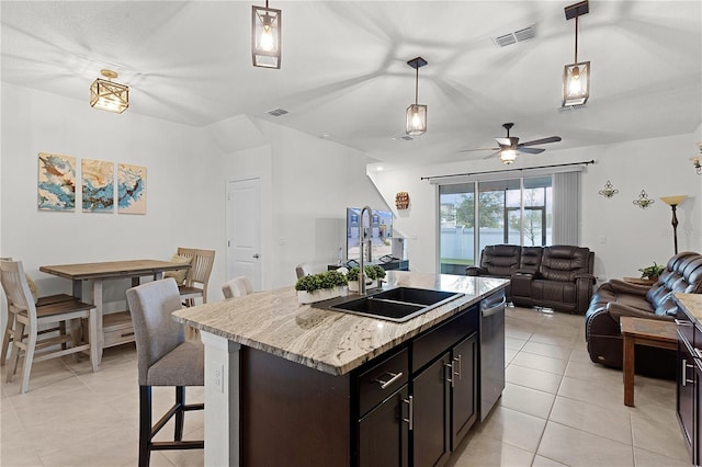 kitchen featuring hanging light fixtures, stainless steel dishwasher, light stone counters, a breakfast bar, and a center island with sink