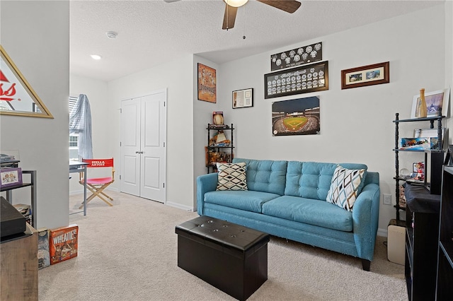 living room with a textured ceiling, carpet flooring, and ceiling fan