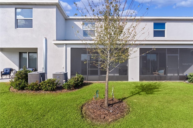 rear view of house with a sunroom, cooling unit, and a lawn