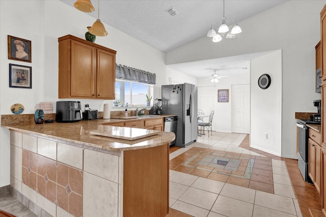 kitchen featuring light tile patterned floors, kitchen peninsula, appliances with stainless steel finishes, vaulted ceiling, and ceiling fan with notable chandelier