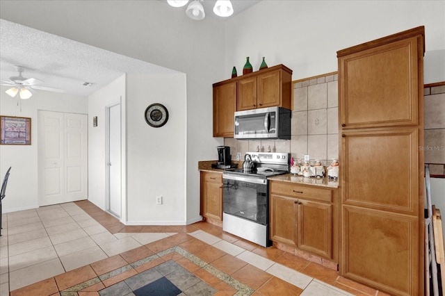 kitchen featuring ceiling fan, decorative backsplash, stainless steel appliances, a textured ceiling, and light tile patterned floors