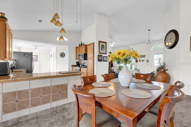 dining area featuring ceiling fan, a textured ceiling, tile patterned floors, and lofted ceiling