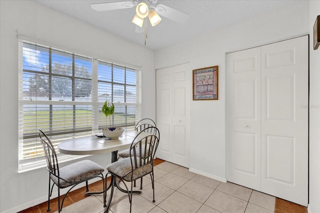 dining area featuring a textured ceiling, ceiling fan, and light tile patterned floors