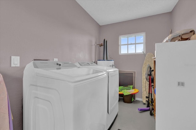 laundry area featuring a textured ceiling, water heater, and washer and dryer